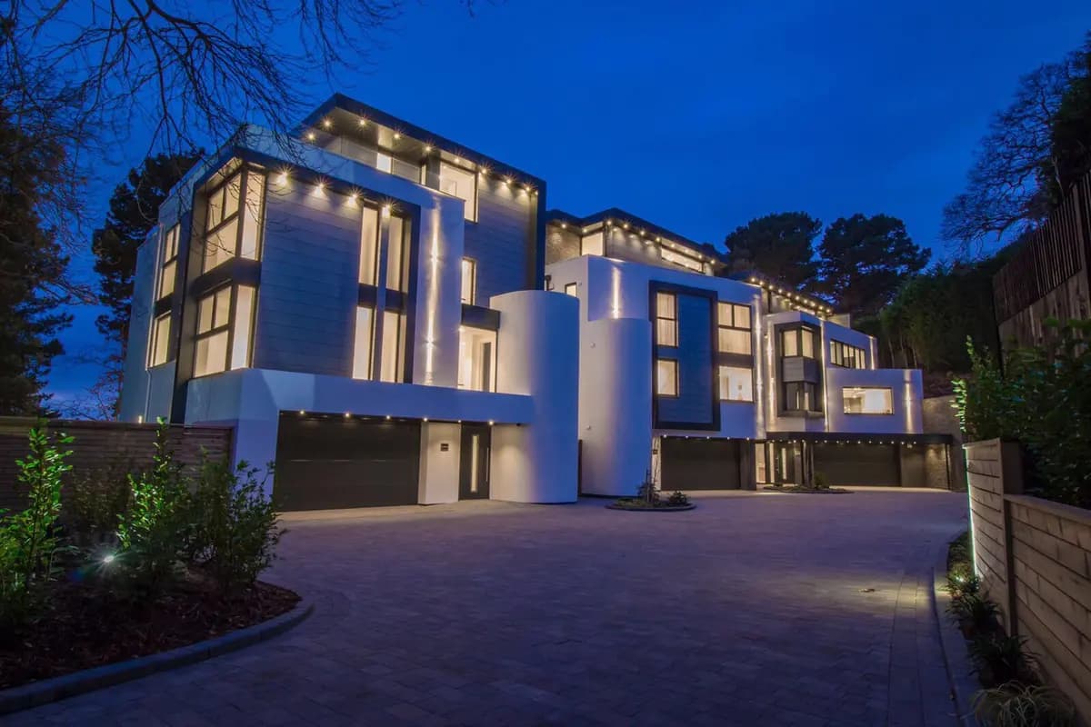 Large house at dusk with extensive exterior lighting