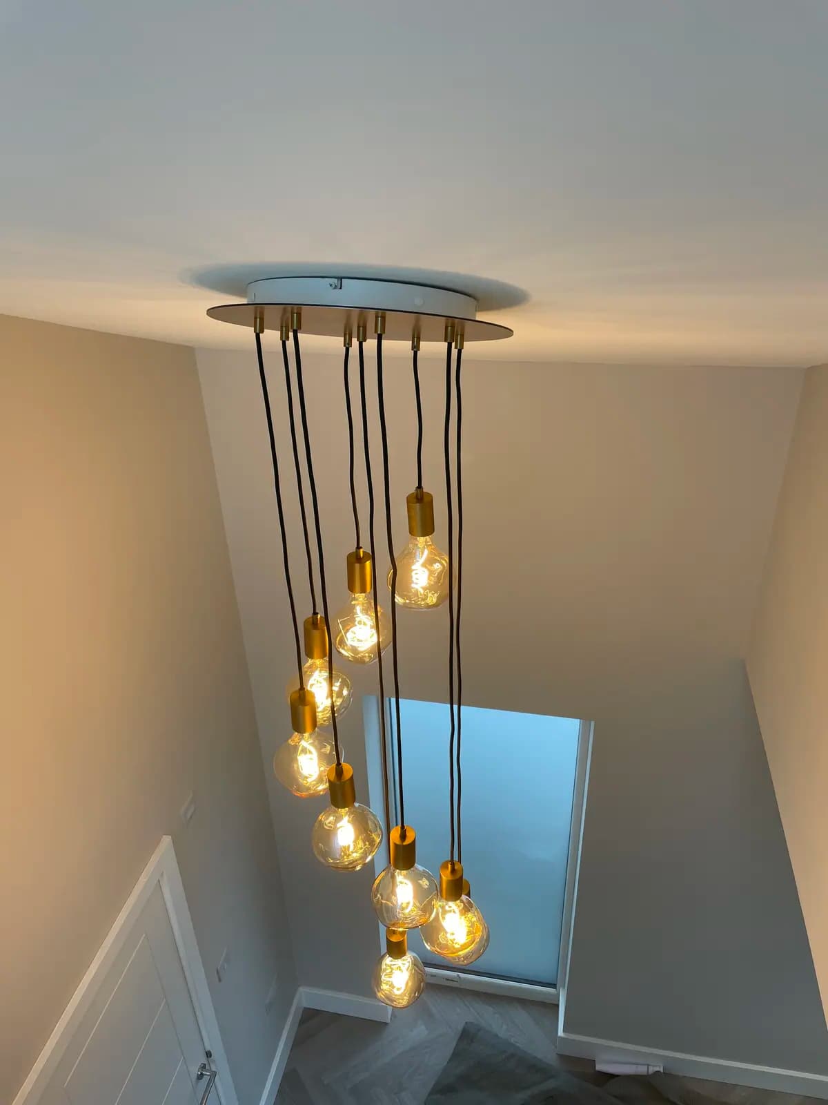 Staircase with decorative multi-pendant lighting cluster